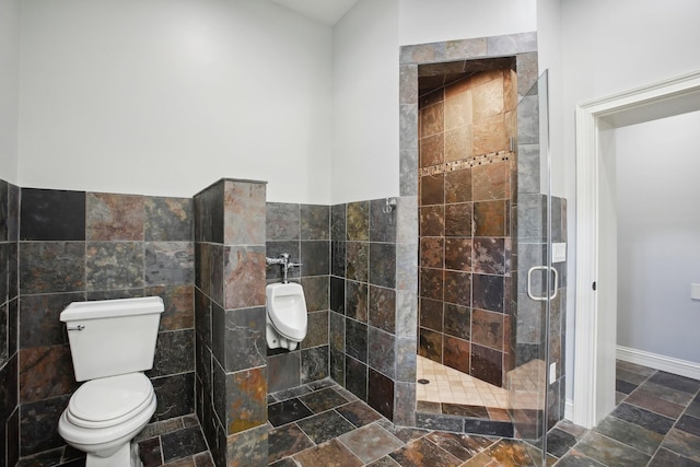 full bathroom with toilet, a shower stall, tile walls, and wainscoting