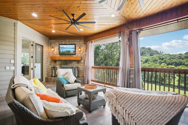 sunroom featuring ceiling fan, an outdoor stone fireplace, and wooden ceiling