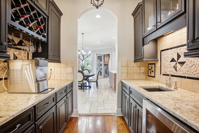 kitchen featuring light stone counters, arched walkways, glass insert cabinets, and a sink