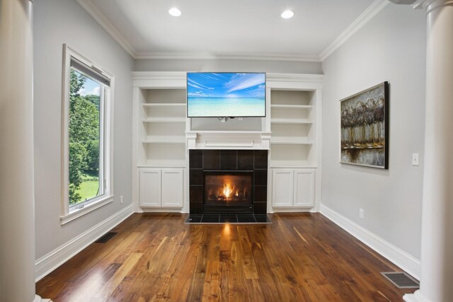 unfurnished living room with built in shelves, a healthy amount of sunlight, visible vents, and baseboards