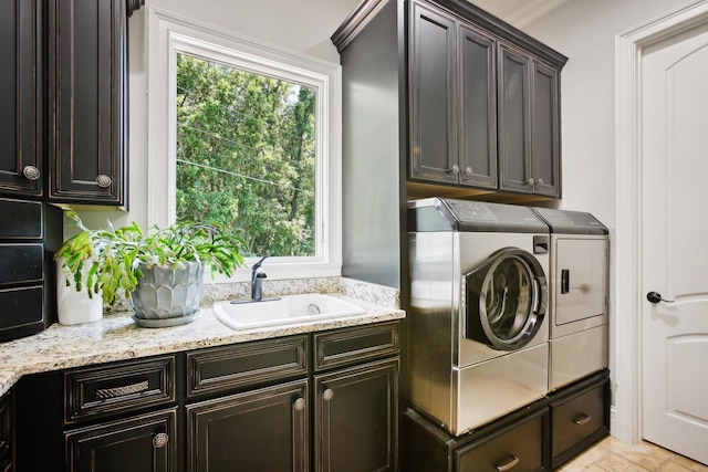 clothes washing area with washing machine and dryer, cabinet space, and a sink