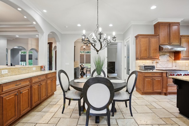 kitchen featuring brown cabinetry, under cabinet range hood, stone tile floors, and light stone countertops