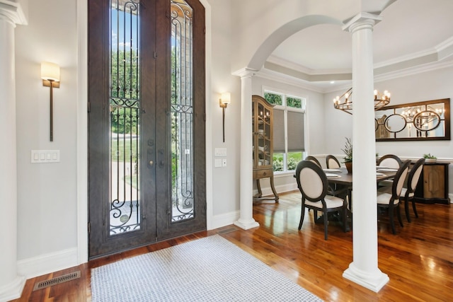 foyer entrance with wood finished floors, visible vents, and ornate columns