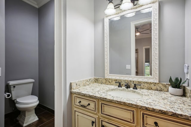 half bathroom featuring vanity, toilet, and baseboards