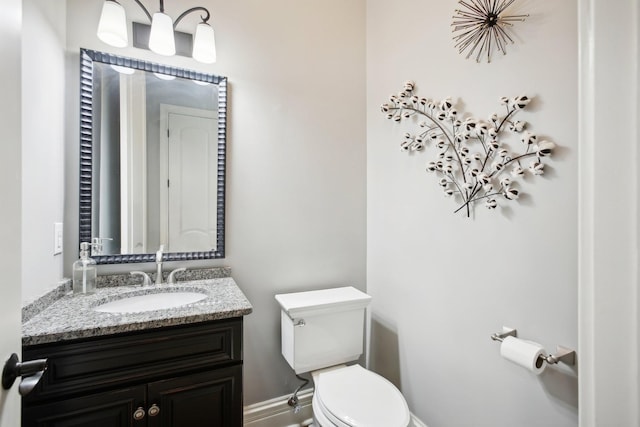 half bath featuring vanity, toilet, and baseboards