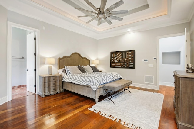 bedroom featuring baseboards, visible vents, a raised ceiling, ornamental molding, and wood finished floors