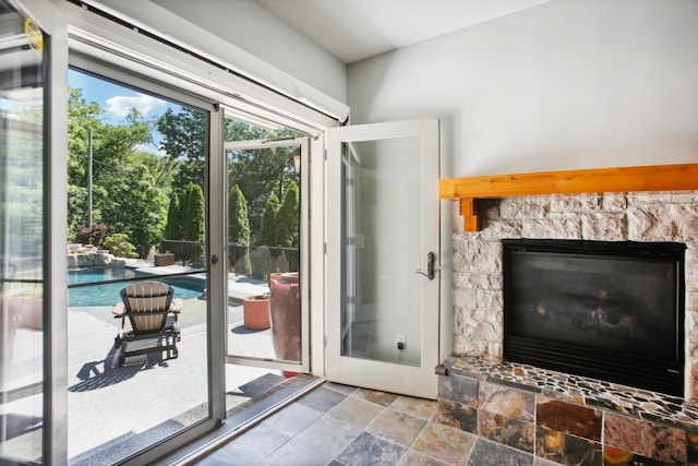 doorway to outside with stone tile floors and a stone fireplace