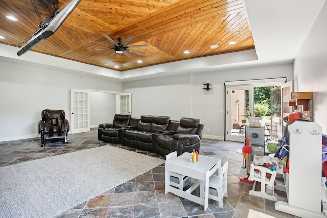 living room with wooden ceiling, baseboards, a tray ceiling, and stone tile flooring