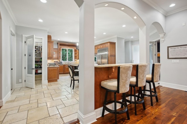 kitchen with brown cabinets, a breakfast bar area, light countertops, built in refrigerator, and baseboards