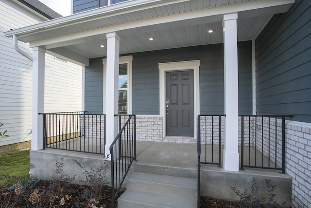 property entrance with a porch and brick siding