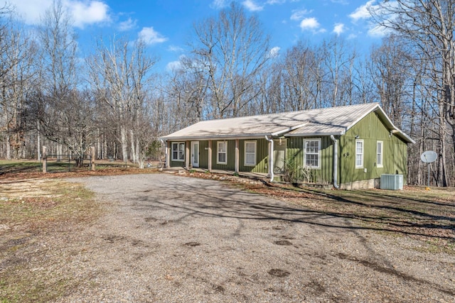 view of front facade featuring driveway, covered porch, central AC unit, and metal roof