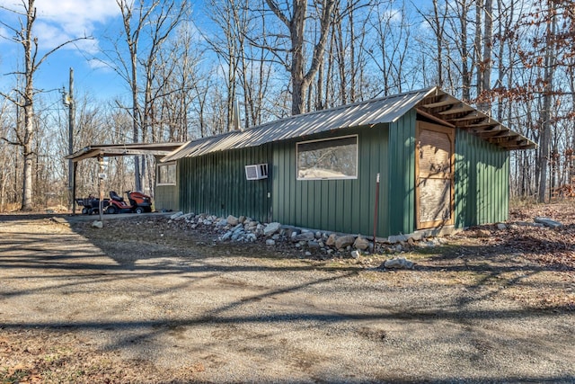 view of side of home with driveway, metal roof, a carport, and an outdoor structure