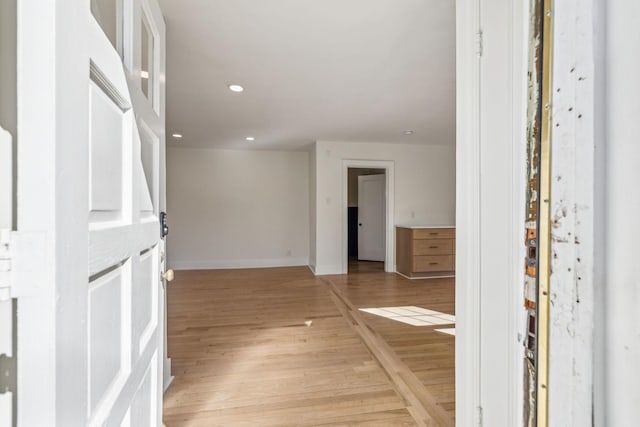 corridor featuring light wood-style flooring, baseboards, and recessed lighting