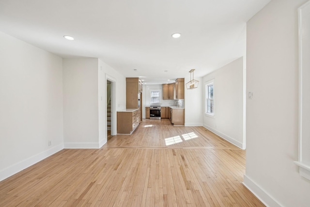 unfurnished living room featuring light wood finished floors, stairs, baseboards, and recessed lighting