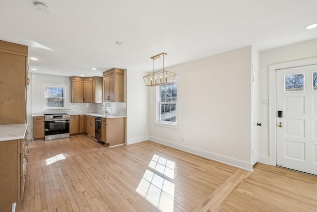 kitchen with stainless steel appliances, light countertops, decorative backsplash, brown cabinetry, and light wood-style floors