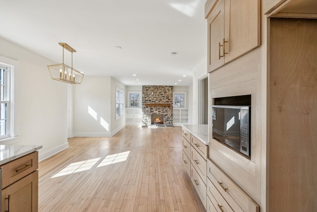 kitchen with a brick fireplace, baseboards, open floor plan, and light wood finished floors