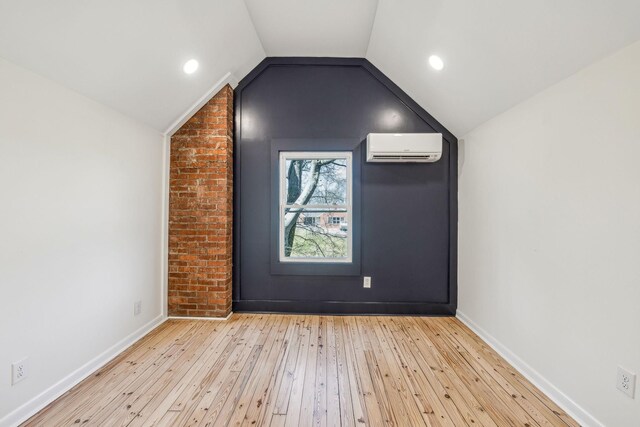 bonus room featuring lofted ceiling, hardwood / wood-style flooring, baseboards, and a wall mounted air conditioner