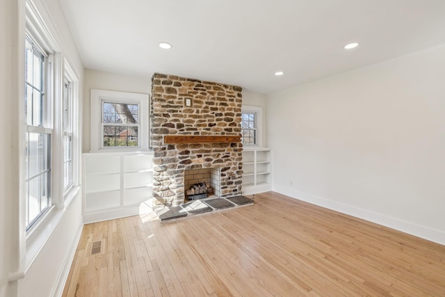 unfurnished living room with a fireplace, light wood finished floors, recessed lighting, visible vents, and baseboards