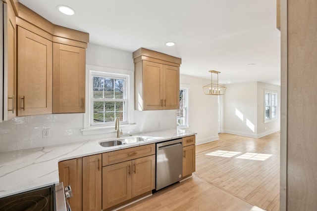 kitchen featuring light stone counters, light wood-style flooring, decorative backsplash, appliances with stainless steel finishes, and a sink