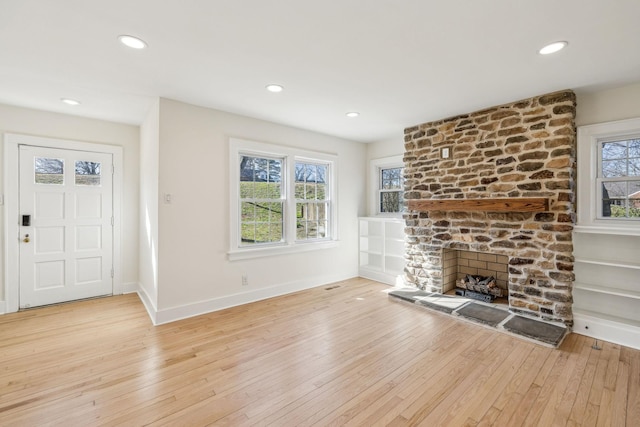 unfurnished living room with a large fireplace, light wood-style flooring, and a wealth of natural light