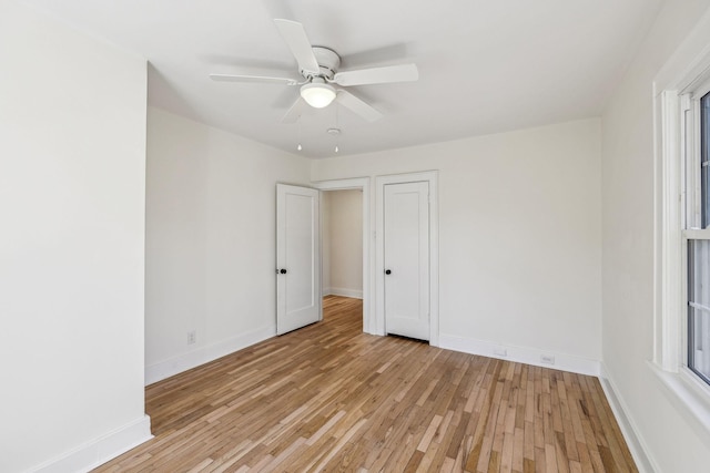 empty room with ceiling fan, light wood-type flooring, and baseboards