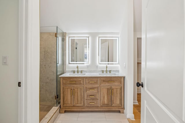 bathroom with a stall shower, a sink, and double vanity