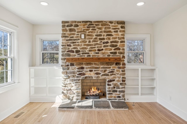 unfurnished living room with a fireplace, wood finished floors, and a healthy amount of sunlight