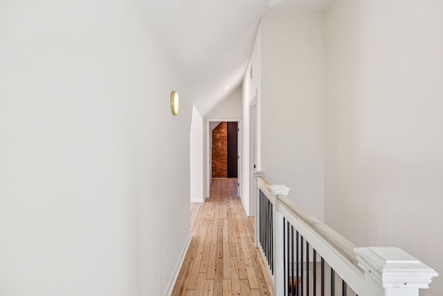 hallway with light wood-type flooring, an upstairs landing, and baseboards