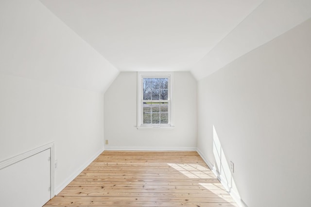 bonus room featuring light wood-style floors, baseboards, and vaulted ceiling