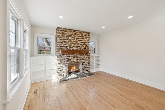 unfurnished living room featuring recessed lighting, visible vents, light wood-style flooring, a stone fireplace, and baseboards