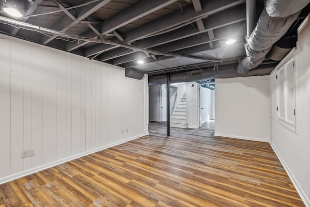 finished basement featuring stairs, wood finished floors, and baseboards