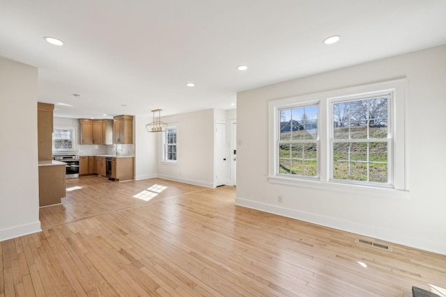 unfurnished living room featuring light wood finished floors, baseboards, and visible vents