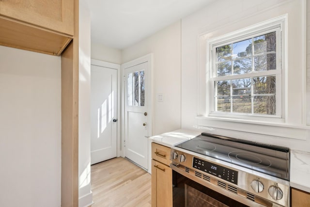 kitchen with light wood finished floors, stainless steel electric range oven, and light countertops