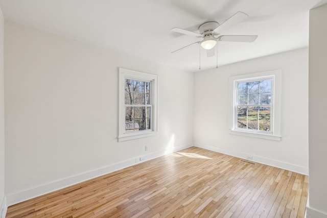 spare room with wood-type flooring, visible vents, baseboards, and ceiling fan