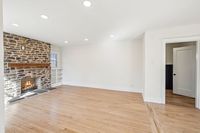 unfurnished living room featuring baseboards, a fireplace, wood finished floors, and recessed lighting