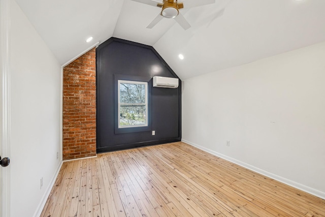 additional living space with baseboards, brick wall, vaulted ceiling, an AC wall unit, and light wood-type flooring