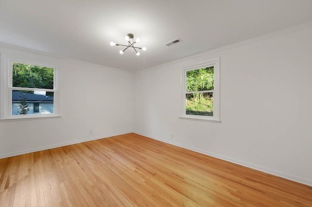 unfurnished room with visible vents, baseboards, ornamental molding, light wood-type flooring, and a chandelier