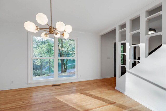 unfurnished dining area with a chandelier, baseboards, visible vents, and light wood-style floors