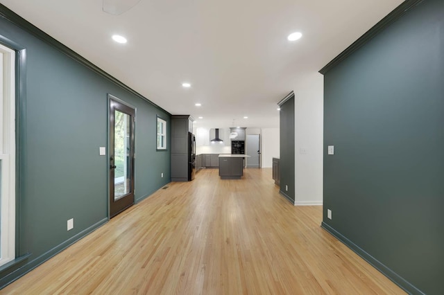 unfurnished living room featuring recessed lighting, crown molding, light wood-style flooring, and baseboards