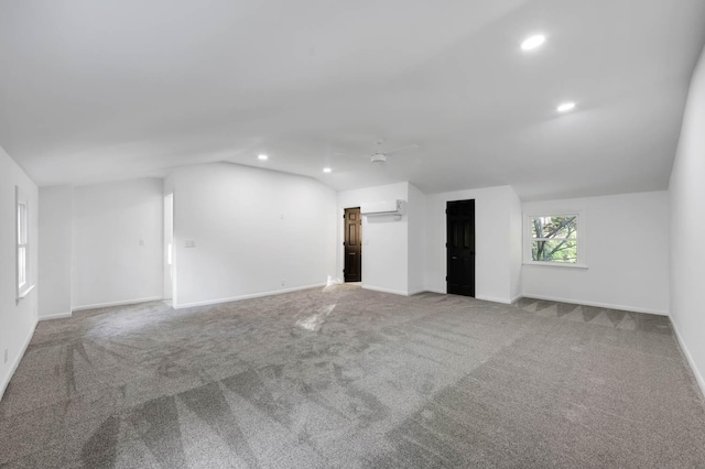 interior space featuring baseboards, vaulted ceiling, carpet flooring, a wall mounted AC, and recessed lighting
