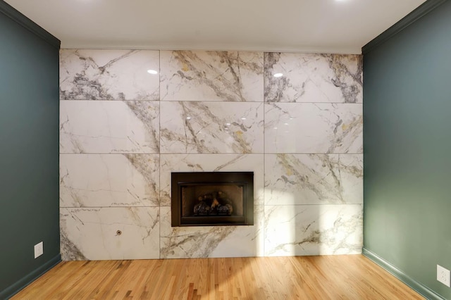 room details with wood finished floors, crown molding, and a premium fireplace