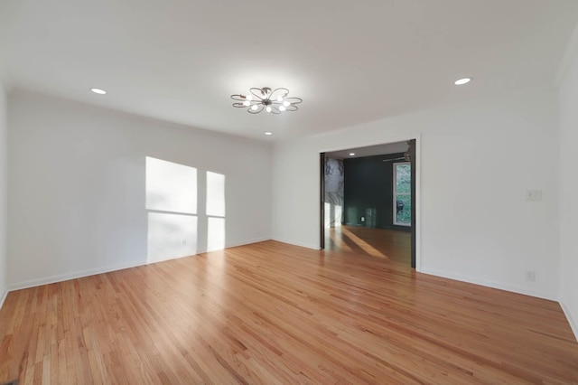 empty room with light wood finished floors, an inviting chandelier, and recessed lighting