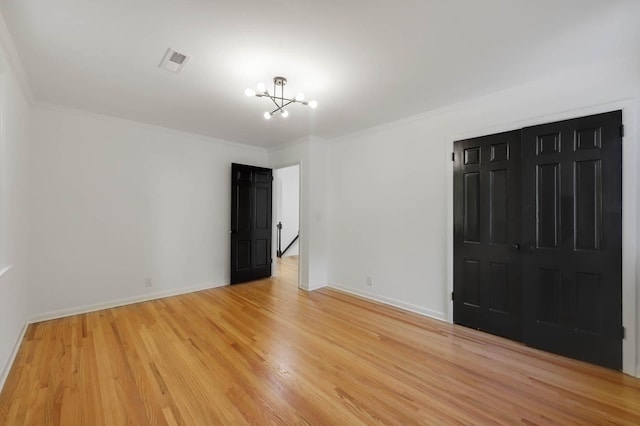 unfurnished bedroom with crown molding, light wood finished floors, visible vents, and a notable chandelier