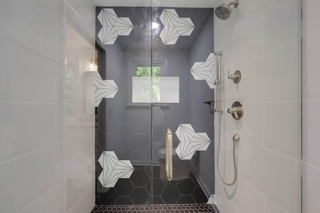 full bath featuring tiled shower, toilet, and tile patterned floors