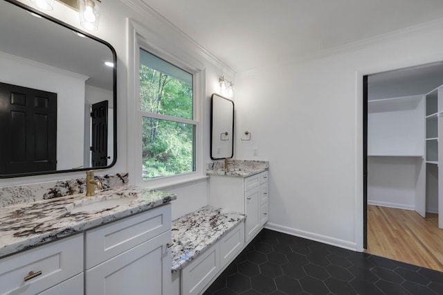 bathroom with tile patterned flooring, crown molding, baseboards, and a sink