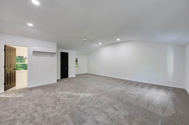 interior space with carpet floors, lofted ceiling, baseboards, and a wall mounted AC