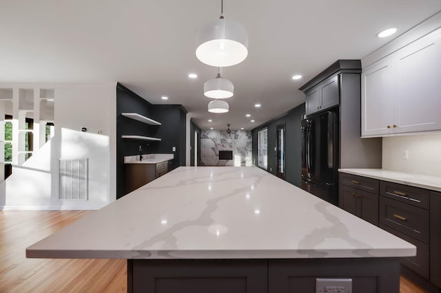 kitchen featuring a center island, tasteful backsplash, visible vents, freestanding refrigerator, and open floor plan