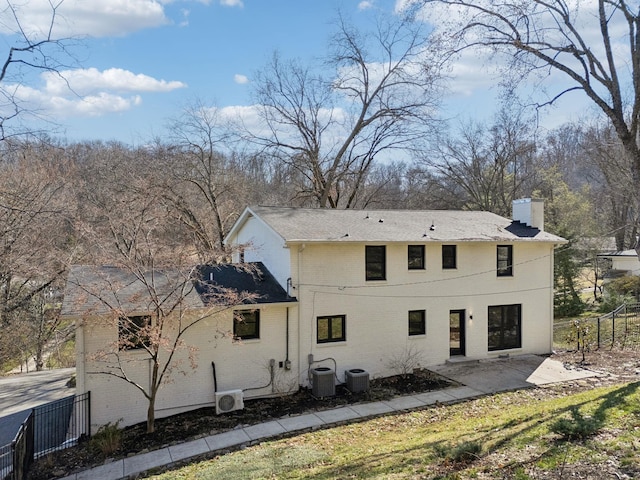 back of property with a patio area, brick siding, fence, and a chimney