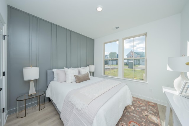 bedroom featuring visible vents, light wood-style flooring, and baseboards