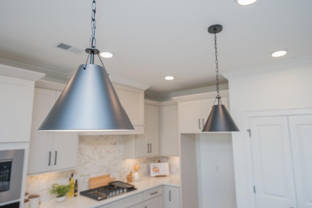 kitchen with decorative light fixtures, range hood, light countertops, gas stovetop, and backsplash